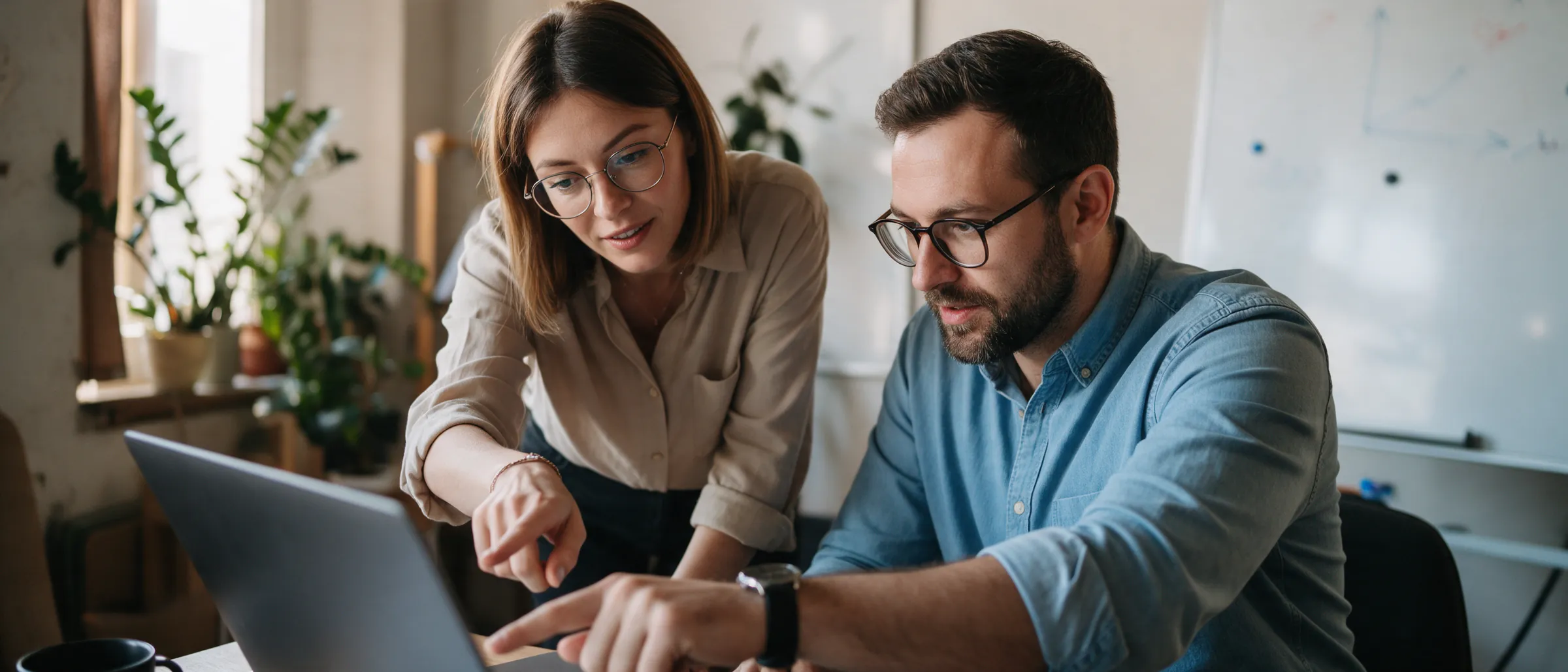 A consultant and a business owner working through a laptop together in a small office